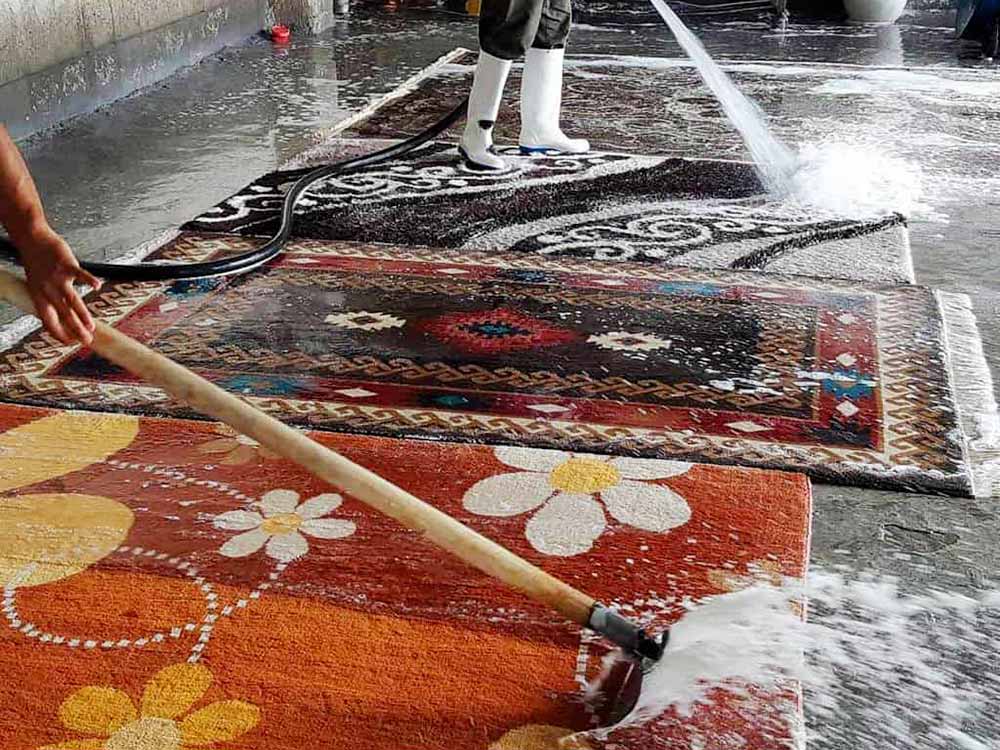 Due persone lavano tappeti persianoi a mano e ad acqua nel centro di lavaggio tappeti a melzo di Bijan Tappeti Pregiati.